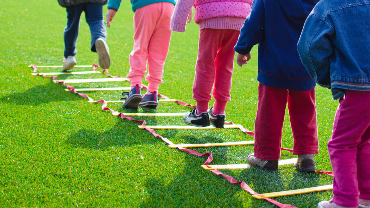 5 niñes jugando en fila en un campo verde