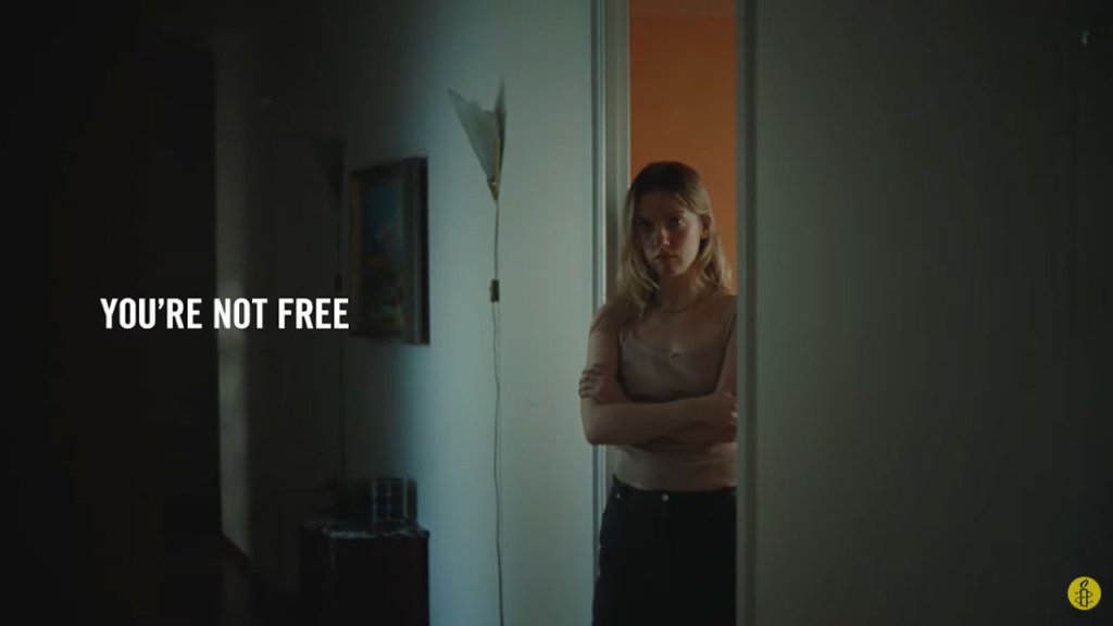Imagen de una chica con la puerta abierta, con la frase "you are not free" (significa "no eres libre).